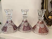 Three Anna Hutte ruby lead crystal candlesticks on shelf