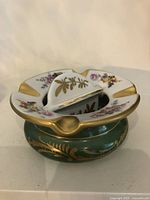 Oblique view showing green base, white rim, gold rests and central lid