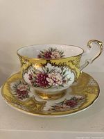 Side view of teacup on saucer showing floral motif, yellow ground and gold gilt