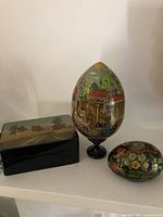 Overview of all three lacquer pieces: rectangular box, large pedestal egg, small floral egg