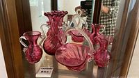 All three cranberry glass pieces inside cabinet