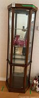 Front view of curio cabinet showing glass door, shelves, mirrored back