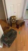 Wall phone, tabletop radio and metal case grouped on floor