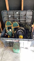 Overview of tote showing snowshoes, backpack, lantern case and other items