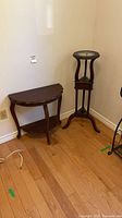 Pedestal and demilune table positioned in corner of room
