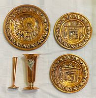 Front view of three wall plates and two vases