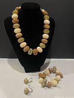 Set on display bust: necklace, bracelet, earrings visible