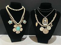 Overall view of two display busts showing all necklaces