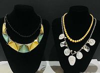 Both necklace displays: triangular bib on left, layered yellow bead and clear acrylic chain necklace on right