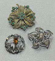 Front view of all three brooches displaying designs and stones