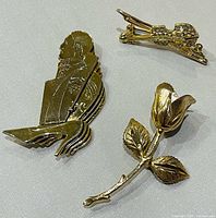 front view of three gold-tone brooches