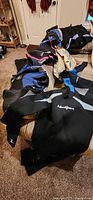 Multiple wetsuits spread on bed showing brand logos and color accents