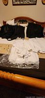 Overview of three tuxedo sets and five dress shirts laid on bed