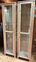 Two natural pine framed glass display cabinets standing side by side