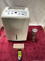 Front view of GE dehumidifier, Tavool moisture meter with box, H2Out canister