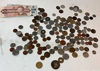 Overview of entire lot: scattered coins and two Canadian banknotes