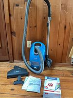 Full lot view showing vacuum, hose, wand, brush, manuals and bag pack