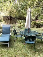 Full view of table, four chairs, chaise lounge, two umbrellas