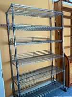 Full view of metal wire shelving unit showing five shelves and casters