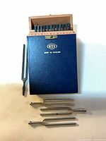 Closed blue case and three loose chrome tuning forks and one black fork