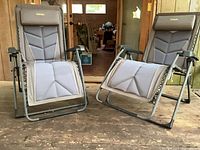 Two matching Cabela's folding chaise lounge chairs set up on wooden floor