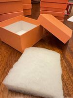 Open orange box with lid and padding shown