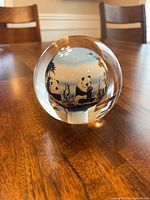 Front view of glass orb showing two pandas and foliage