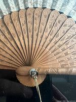 Carved wooden fan guard detail within shadow box