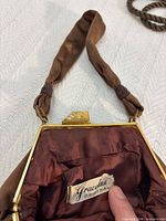 Interior view of brown Graceline wristlet showing label, gold-tone frame and fabric strap
