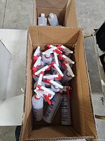 Box containing multiple F-2 Sprayer bottles with red/white triggers and adjacent box of capped bottles