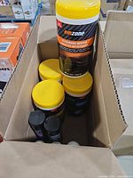 open cardboard box showing 4 emzone wipe canisters, 3 black spray cans, 2 metal cans