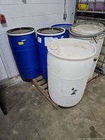 Three blue and two white plastic drums on pallet