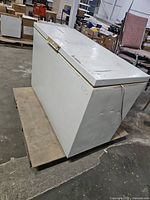 Full view of closed white chest freezer on pallet showing exterior condition and power cord