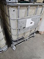 Front view of IBC tote showing plastic tank, metal cage, and pallet base