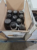 Box with black-capped Emzone aerosol cans