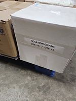White carton labelled Isolation Gowns size Large qty 15 next to other boxes