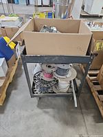 Full view of cart with box of metal boxes on top and wire spools below