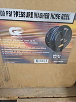 Box showing product image and specifications: 5000 PSI pressure washer hose reel, capacity, mounting info