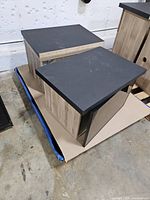 Two woodgrain laminate wall cabinets on pallet, black tops visible