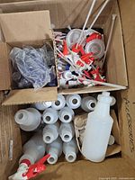 Overview of box with white spray bottles, trigger heads, additional caps