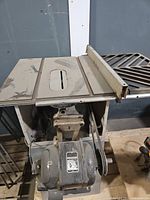 Top view of table saw showing cast iron surface, miter slots, rip fence, motor and belt drive visible