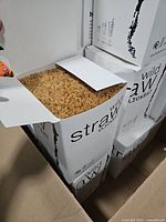 Open box showing large quantity of tan wooden straws packed tightly