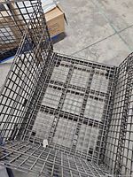 Interior view of assembled steel wire mesh pallet cage showing grid base and walls