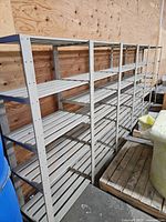 Full view of grey slatted wood shelving against plywood wall