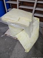 Large roll and folded batt of yellow fiberglass insulation on pallet