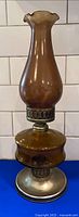 Full view of amber glass oil lamp with chimney, burner, and metal base