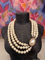 Full view of triple strand faux pearl necklace on display bust