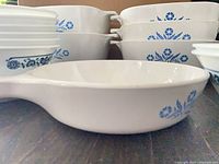 Stacks of Cornflower Blue casseroles and handled Grab-It dish in foreground