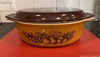 Side view showing fruit motif on casserole and lid fit