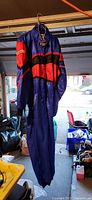 Full view of blue Resma race suit hanging, shows overall color and design